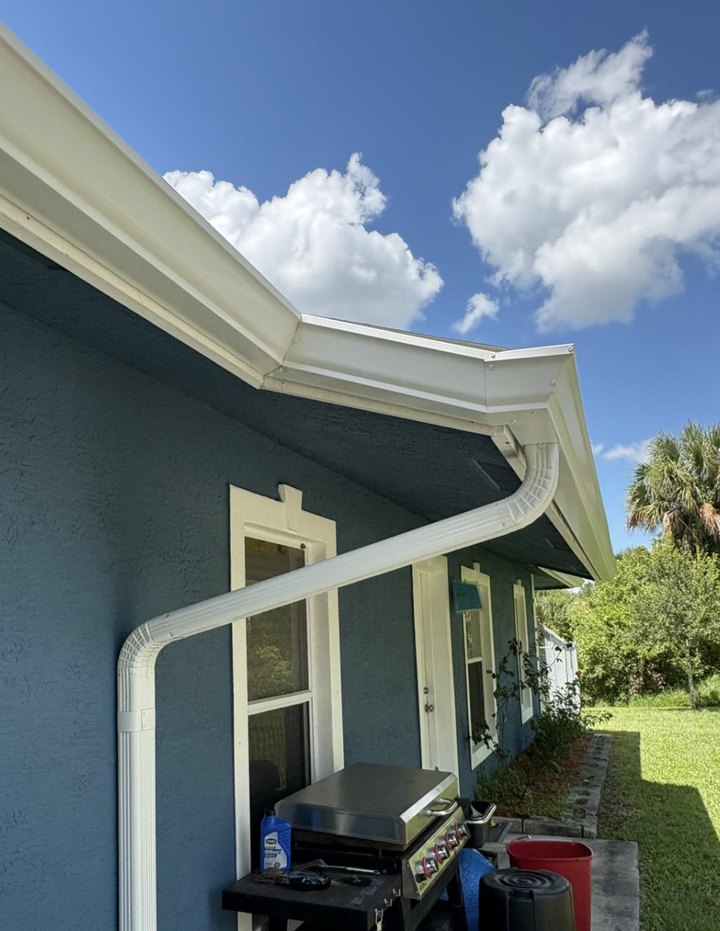 Seamless white K-style gutter and downspout on a blue Port St. Lucie home