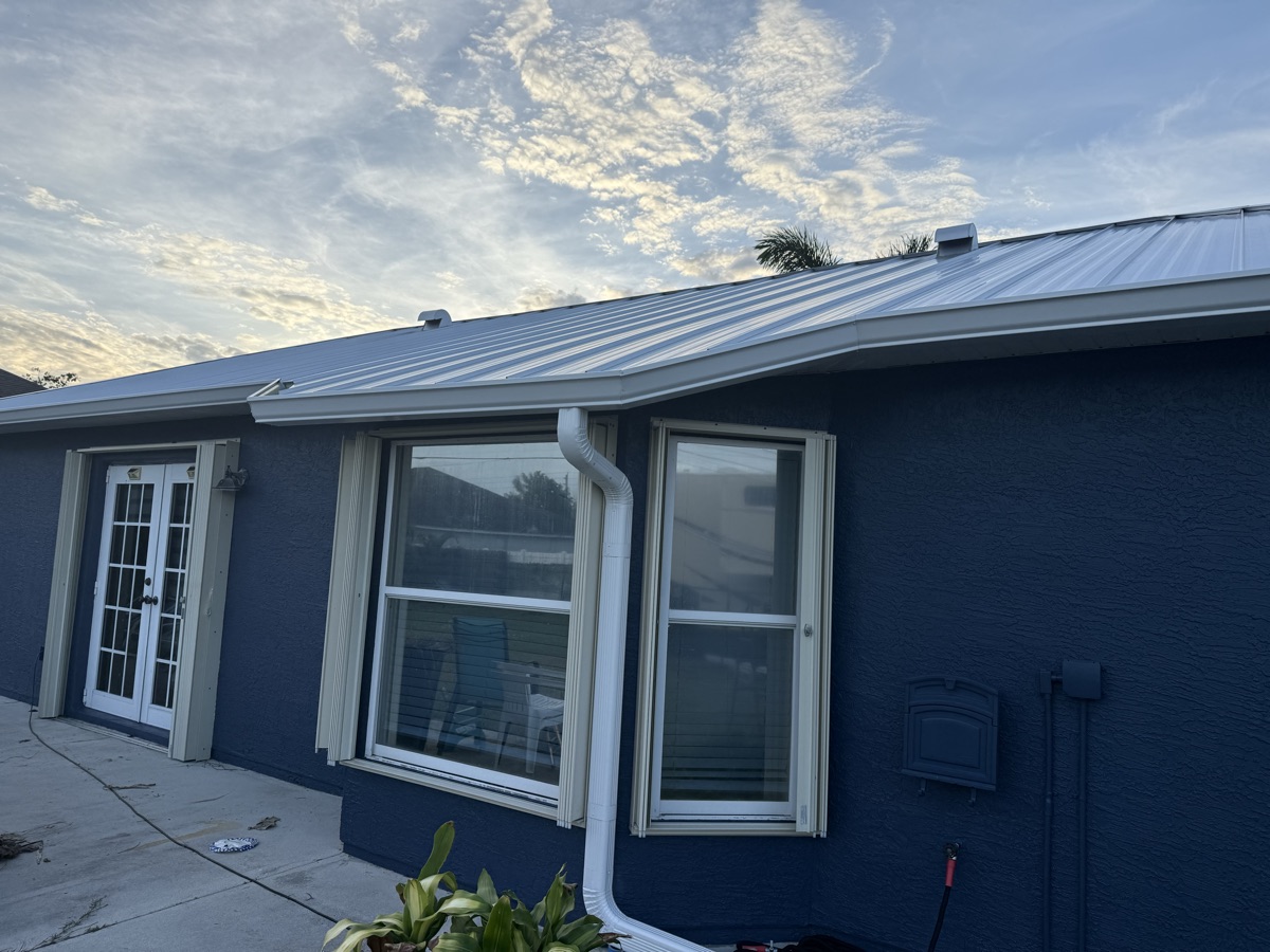 Navy home with metal roof and white seamless gutters